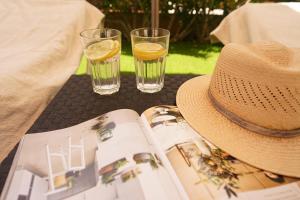 un chapeau, deux verres d'eau et un livre sur une table dans l'établissement Maspalomas Suite by "The Stay Las Palmas" VV, à Maspalomas