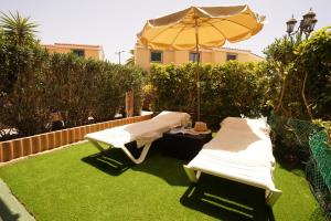 twee ligstoelen en een parasol op het gras bij Maspalomas Suite by "The Stay Las Palmas" in Maspalomas