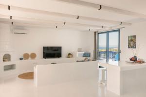 a white living room with a tv and a couch at Villa Giasemi-Iris sunset villas in Lépedha