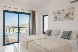 two beds in a room with a large window at Villa Giasemi-Iris sunset villas in Lépedha +36 photos