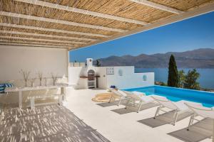 a patio with white chairs and a swimming pool at Villa Giasemi-Iris sunset villas in Lépedha