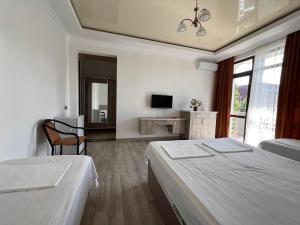 a white bedroom with two beds and a television at GARDEN IN GONIO MATATA MOTSIKULIS 58 in Batumi