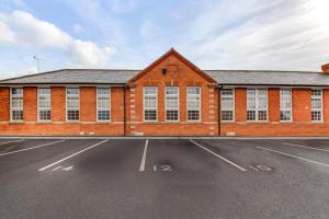 a red brick building with white windows in a parking lot at Stylish & Contemporary 2-Bedroom House in Worksop