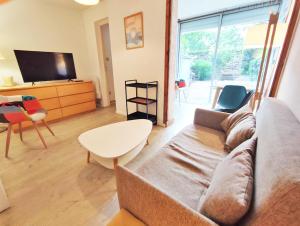 een woonkamer met een bank en een tv bij Le Sentein, T2, centre, parking, jardin, 2 personnes in Luchon