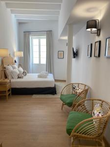 a bedroom with a bed and two chairs and a window at Hotel Maïa in Ciutadella