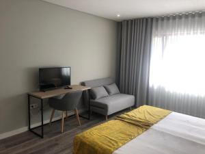Schlafzimmer mit einem Bett, einem Schreibtisch und einem TV in der Unterkunft Hostel S. Miguel FitNCare in Guarda