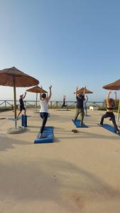 a group of people doing yoga on the beach at Hotel Mare Pineta in Santa Margherita di Pula