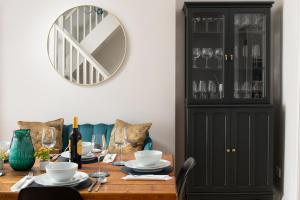 a dining room table with a black cabinet and a mirror at Nythfa in Llanrwst
