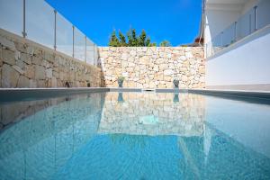 a swimming pool with a stone wall and blue water at Villa Carlotta con piscina in Noto Marina