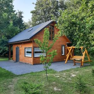 uma cabana de madeira com um banco e um parque infantil em 3 kroki od sosny Domek w lasku Sitaniec em Zamość
