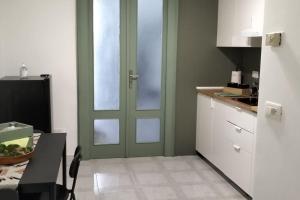 a kitchen with a green door and a table and a counter at Alloggio privato "Ballatoio233" in Bisceglie