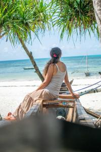 a woman sitting on a boat on the beach at Ladha ya Zanzibar Boutique Guesthouse in Jambiani