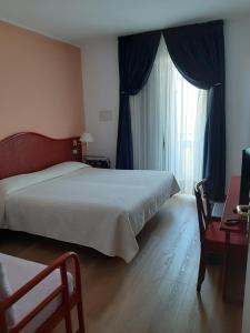 a bedroom with a bed and a window with blue curtains at Hotel Beny in Lido di Jesolo