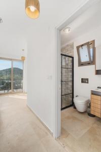 baño blanco con aseo y ventana en Bal Butik Otel, en Datça