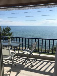 a table and chairs on a balcony with the ocean at Elena's Beach house in Nea Irakleia