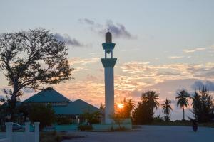 a clock tower with the sunset in the background at Maaniya Palace in Maamigili