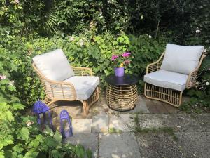 2 chaises en osier et une table dans le jardin dans l'établissement am Heider Bergsee, à Brühl