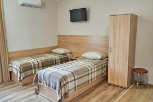 Habitación con 2 camas y TV en la pared. en Каприз en Kamianets-Podilskyi