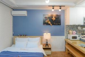 a bedroom with a blue wall with a bed and a kitchen at Suncheon Bay Healing Pension in Suncheon