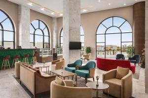 a lobby with chairs and tables and windows at Ramada by Wyndham Karapinar in Karapınar