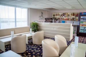 una sala de espera con sillas blancas y un bar en Bella Marina en Carasuhatul-de-Sus