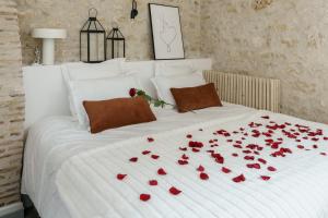 a white bed with red roses laying on it at My Home Prestige / SPA Privatif in Châteauroux