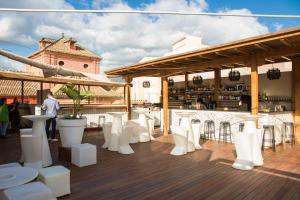 a rooftop deck with white chairs and a bar at Apartamentos Málaga Premium - Calle San Telmo in Málaga