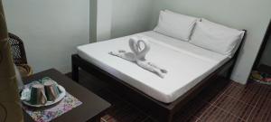 a bed with white sheets and a ribbon on it at ALFA Garden Lodge in El Nido