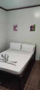 a bed in a room with white sheets and two pictures on the wall at ALFA Garden Lodge in El Nido