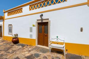 ein gelbes und weißes Gebäude mit einer Tür und einem Stuhl in der Unterkunft Casa do Forno (Vale Luis Neto-Retiro do Caldeirão) in Loulé