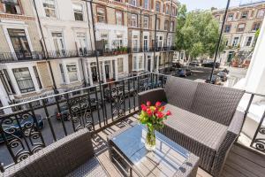 a balcony with a table with a vase of flowers on it at Stay at Kensington and Knightsbridge in London