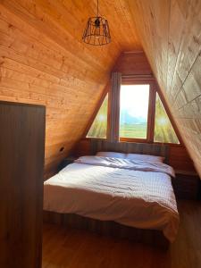 Hotel Skiatori 2 في Kukës: سرير في غرفة خشبية مع نافذة