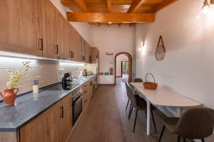 a kitchen with wooden cabinets and a table and chairs at Casa do Forno (Vale Luis Neto-Retiro do Caldeirão) in Loulé