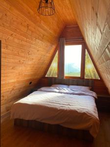 Hotel Skiatori 2 في Kukës: سرير في غرفة خشبية مع نافذة