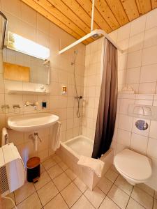 Hotel Wildbach Brienz في برينز: حمام مع حوض ومرحاض وحوض استحمام