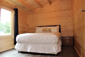 1 dormitorio con 1 cama en una cabaña de madera en Inviting 3-Bedroom Lodge in Ashton Under Hill, en Evesham