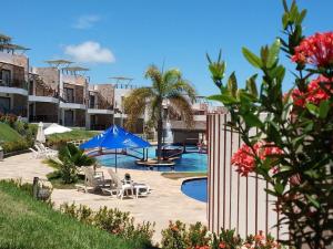 uma piscina com cadeiras e guarda-sóis num resort em Pipa Brisas do Amor em Pipa