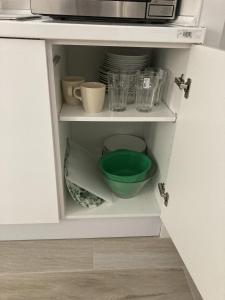 un armario con cuencos, platos y microondas en Casa de Huéspedes Cinco Torres en Madrid