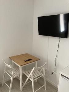 una mesa y sillas con TV en la pared en Casa de Huéspedes Cinco Torres, en Madrid