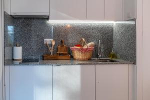 a kitchen counter with white cabinets and a sink at O rincón dos Sentidos in Cenlle