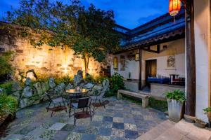 a patio with a table and chairs and a stone wall at Tianyiju Inn - Suzhou Tongli Ancient Town in Suzhou