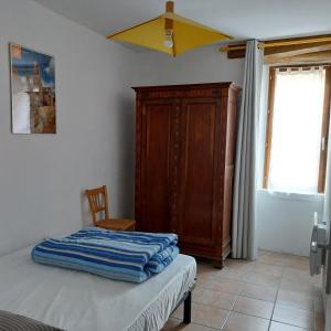 1 dormitorio con 1 cama y armario de madera en Gîte le Petit Riou, en Sainte-Marguerite-Lafigère