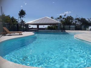 a swimming pool with a bench and a gazebo at Maison F3 mitoyenne avec piscine partagée et jardin privatif - Résidence Plaiz'Anse in Petite Île