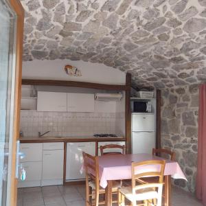 cocina con mesa y pared de piedra en Gîte le Petit Riou, en Sainte-Marguerite-Lafigère