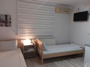 um pequeno quarto com uma cama, uma mesa e uma janela em Apartments Sofija em Niš