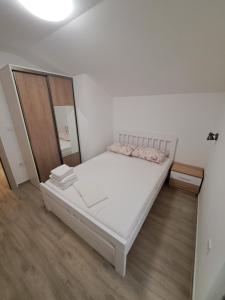 a bedroom with a white bed and a wooden floor at Guest House Martinovic in Bečići