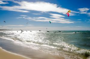 Un groupe de gens volant des cerfs-volants dans l'océan dans l'établissement Beach Place Deluxe Apartment Cumbuco Sea View, à Cumbuco