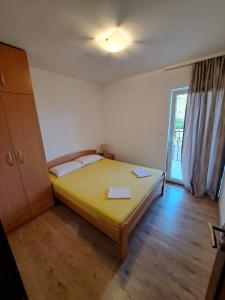 a bedroom with a yellow bed and a window at Guest House Martinovic in Becici