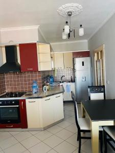 una cocina con armarios rojos y blancos y una mesa en Welcome home, en Kukës