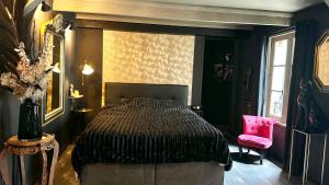 1 dormitorio con 1 cama y 1 silla rosa en LA BLACK ROOM / Les suites romantiques à Honfleur centre historique, en Honfleur
